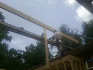 Carpenter setting a ridge beam over a new addition frame — Ice Dam Removal by Roofing Brothers in Millwood