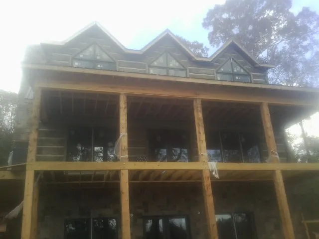 Dormers and porch framing on a large log home under construction — Roof Coating work by our crew in Millwood