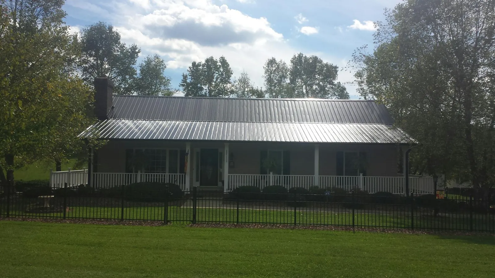 Gray metal roof on a brick ranch with a full width front porch — Gutter Guard Installation work by our crew in Millwood