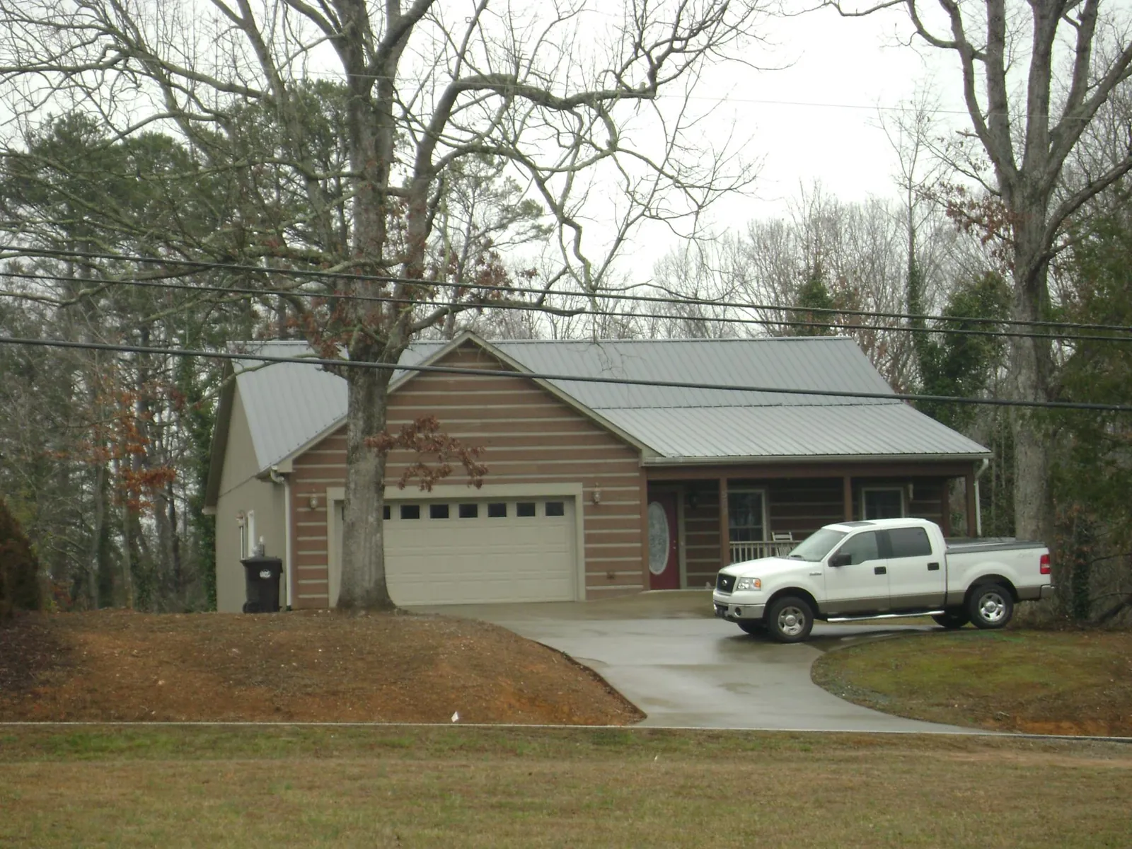 Gray metal roof on a log sided house with an attached two car garage in Millwood