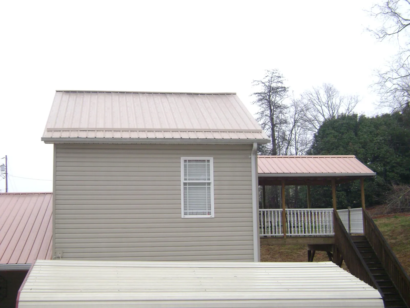 Tan metal roofs on a two story addition and attached porch, from a Roof Replacement job in Millwood